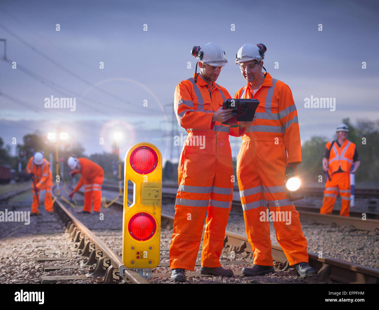 Les travailleurs d'entretien ferroviaire using digital tablet at night Banque D'Images