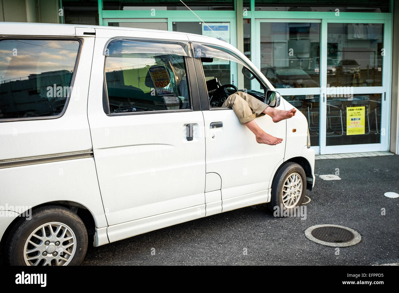 Un homme prend une sieste dans sa voiture. Banque D'Images