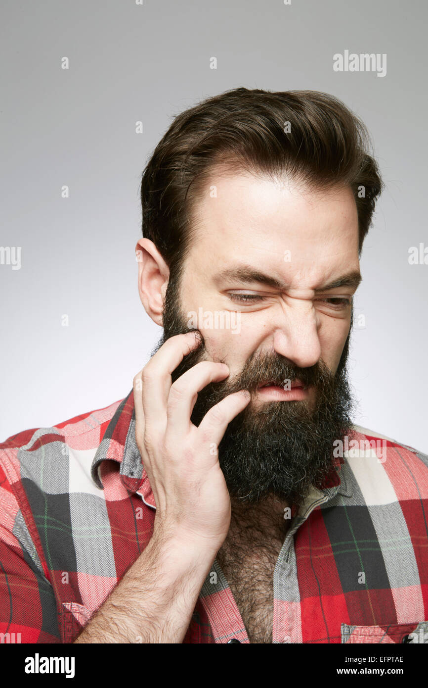 Studio portrait de jeune homme envahi par la barbe gratter Banque D'Images