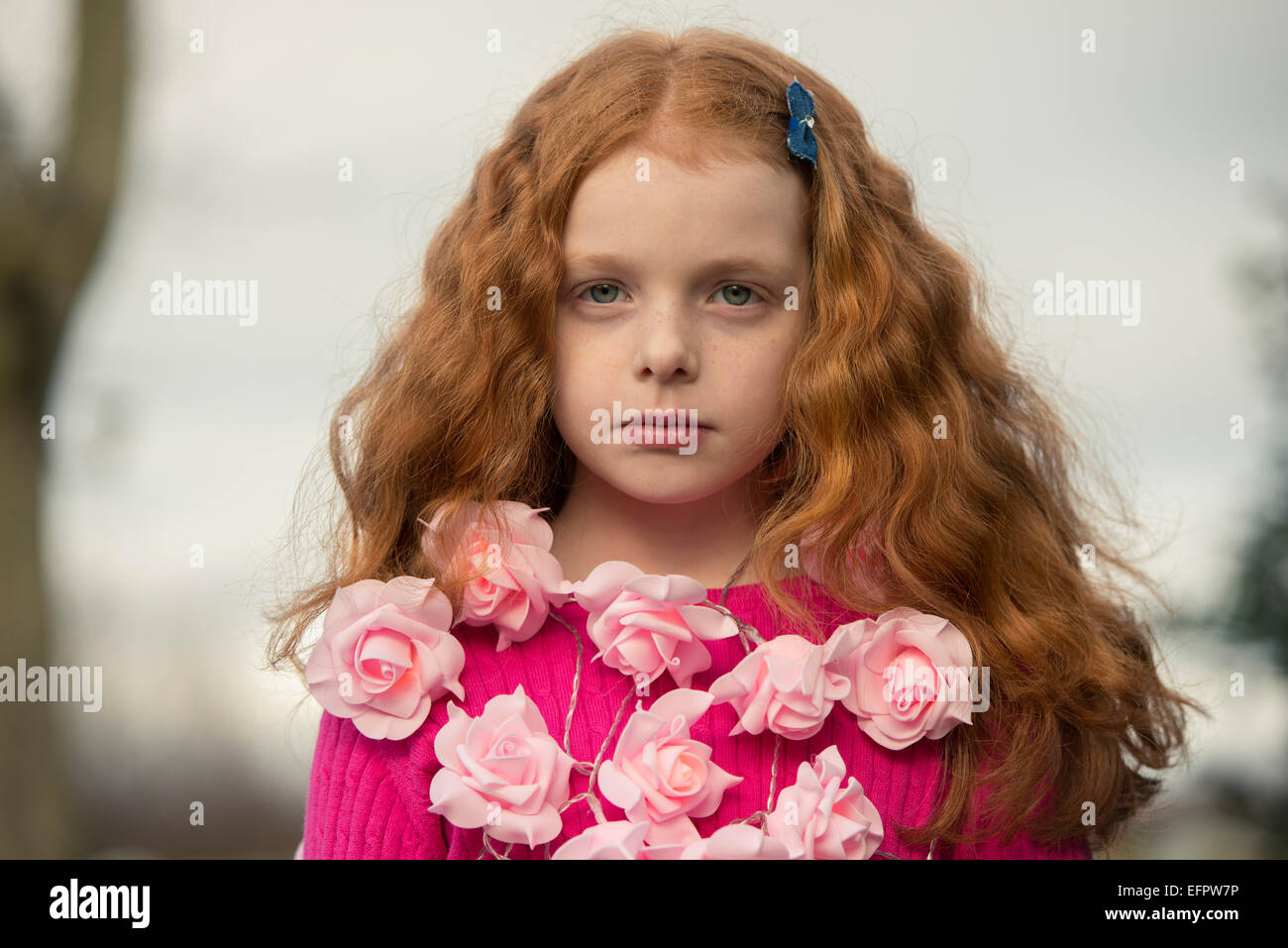 Portrait d'une petite fille avec une rose guirlande autour de son cou. Banque D'Images