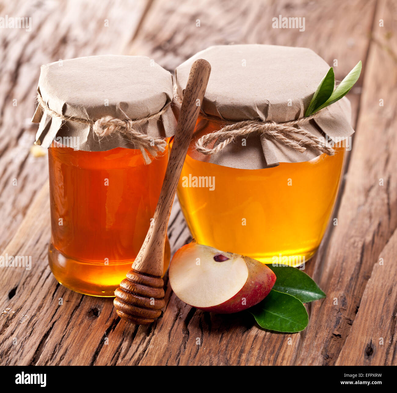 Les canettes en verre plein de miel et de morceau de pomme sur la vieille table en bois. Banque D'Images