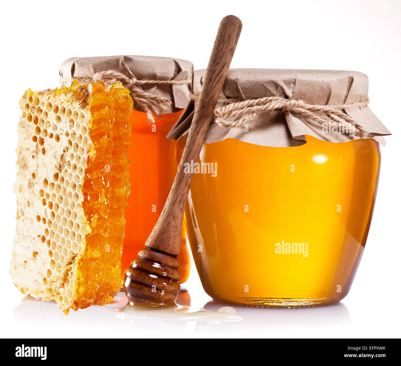 Les canettes en verre pleine de miel, miel et bâton en bois sur fond blanc. Banque D'Images