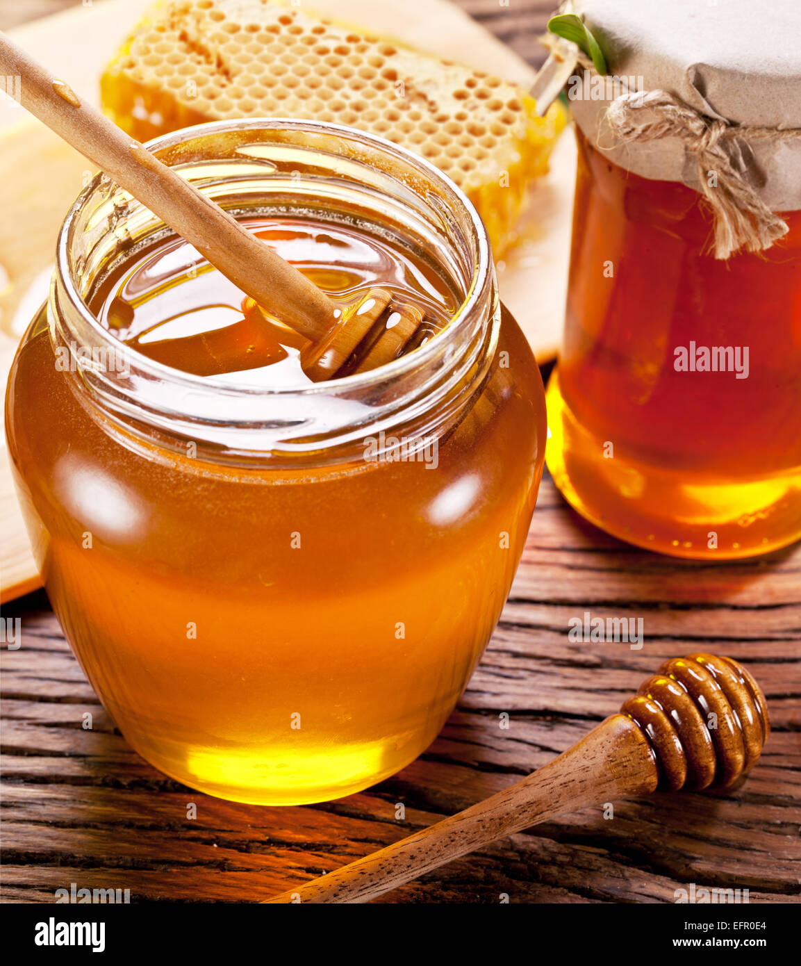Balancier en bois en verre est plein de miel sur la table en bois. Banque D'Images