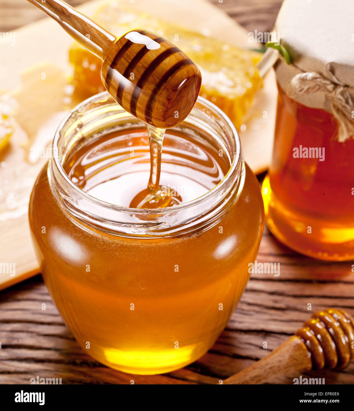 Le miel qui coule dans le verre peut de bâton en bois. Banque D'Images