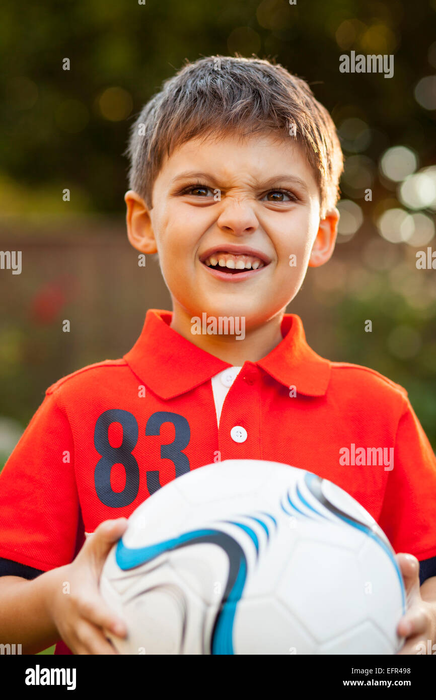 Garçon avec football, making faces Banque D'Images