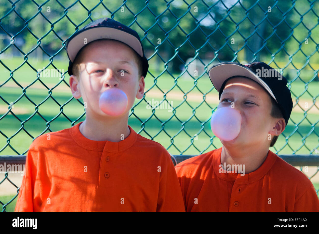 Deux jeunes joueurs de baseball masculin faisant des bulles avec bubblegum Banque D'Images