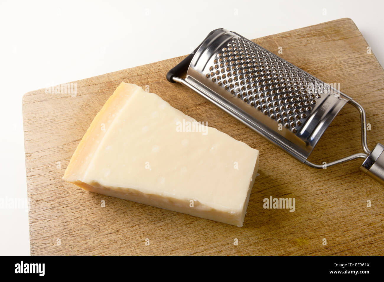 Bloc de fromage Parmesan et une râpe sur une planche à découper en bois Banque D'Images