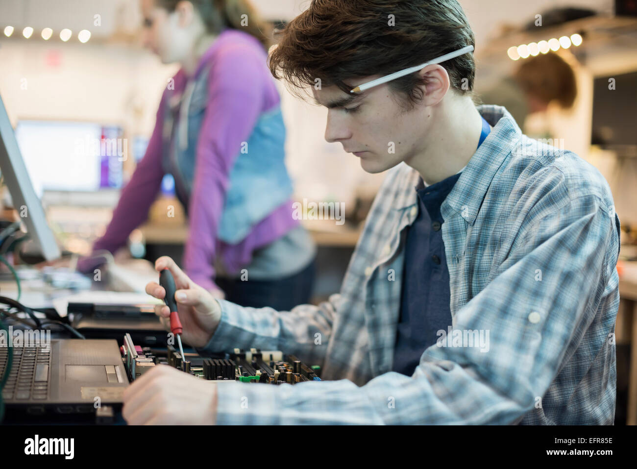 Deux personnes dans un atelier de réparation d'ordinateur. Des techniciens, des jeunes qui travaillent à réparer les ordinateurs. Banque D'Images