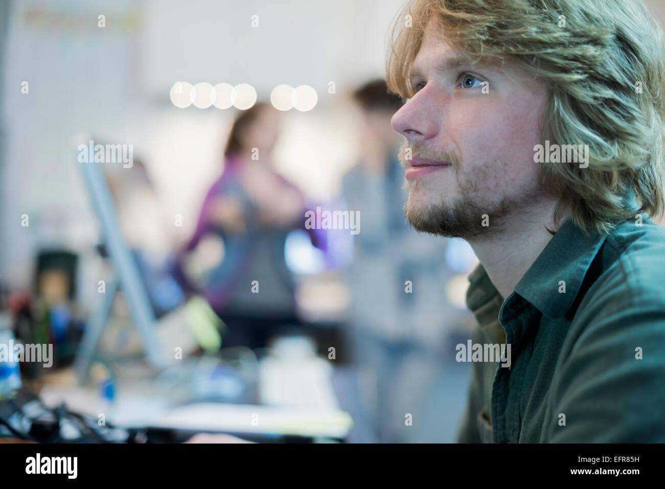Un homme à la recherche de sa tâche dans un atelier de réparation d'ordinateur. Banque D'Images