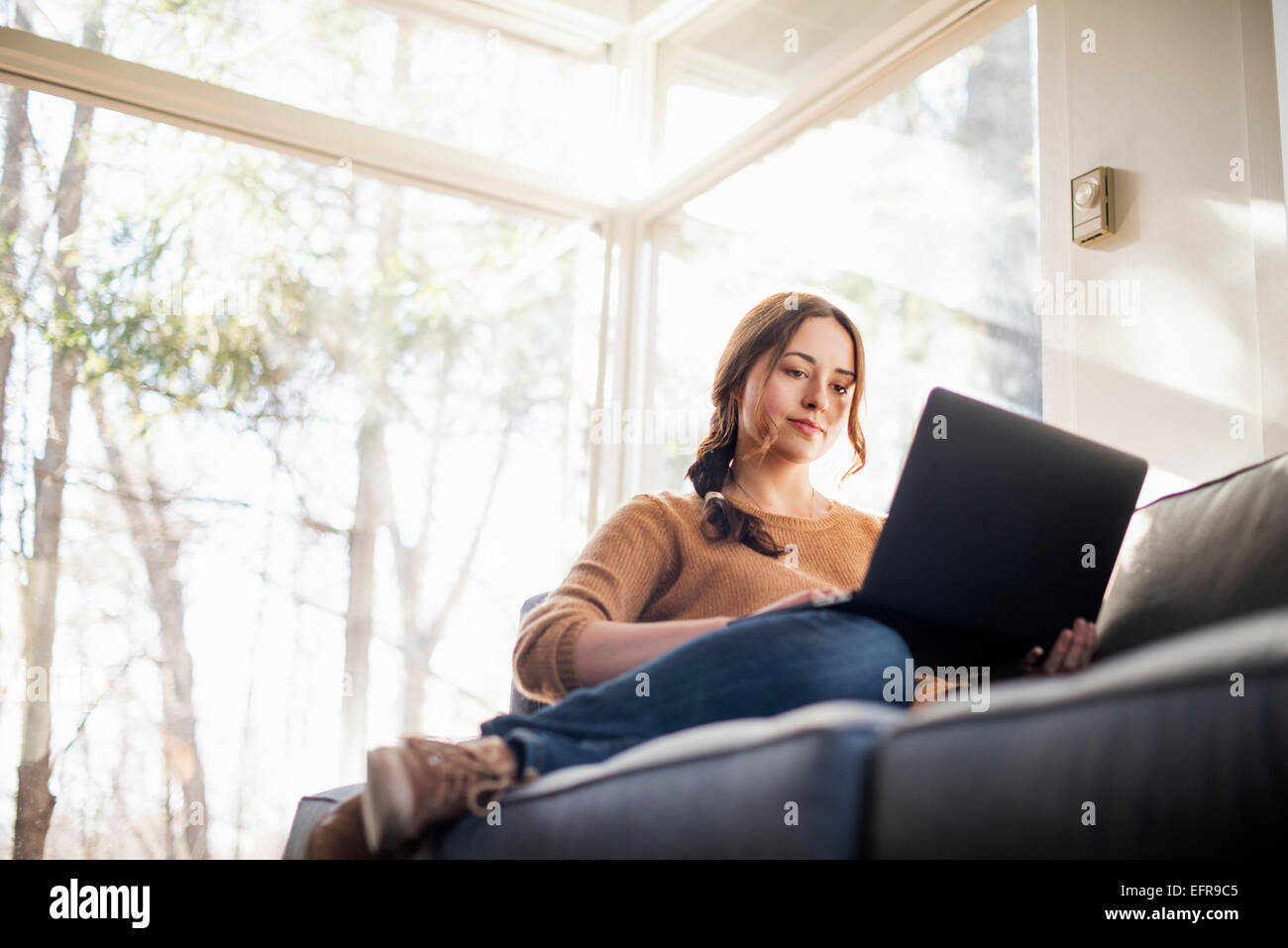 Portrait d'une femme assise sur un canapé en regardant son portable. Banque D'Images Portrait d'une femme assise sur un canapé en regardant son portable. Banque D'Images