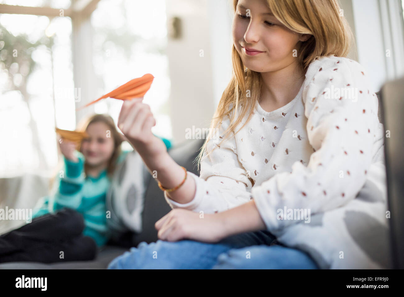 Deux filles assis sur un canapé, holding paper d'oiseaux. Banque D'Images
