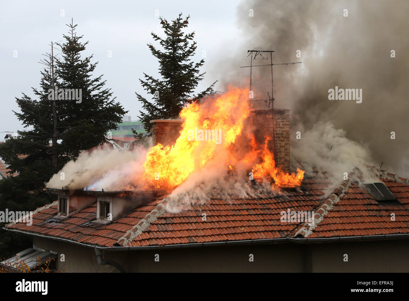 Un toit de maison en feu et de la fumée. Banque D'Images