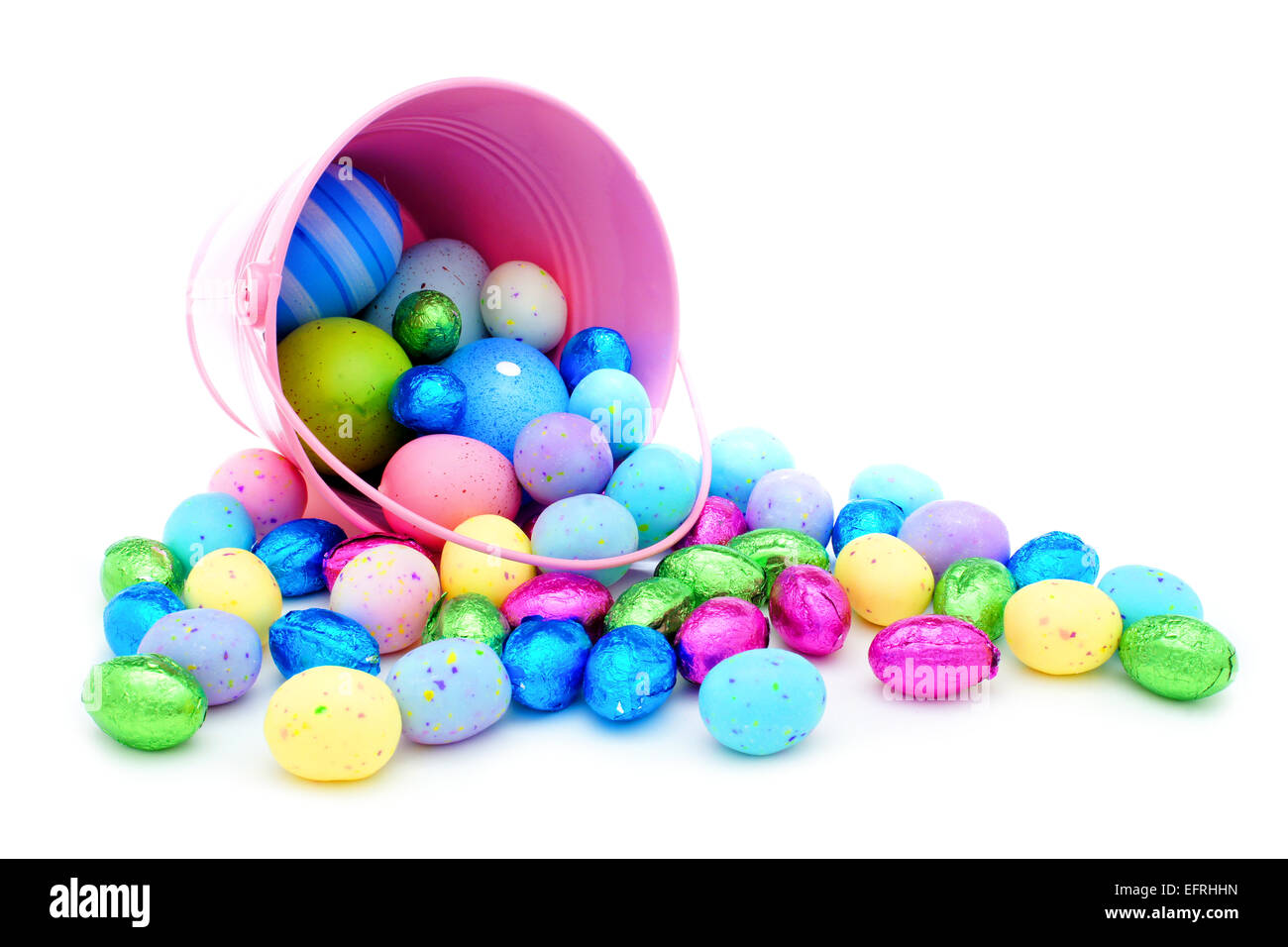 Seau de Pâques rose déversant des œufs en chocolat et des bonbons colorés Banque D'Images