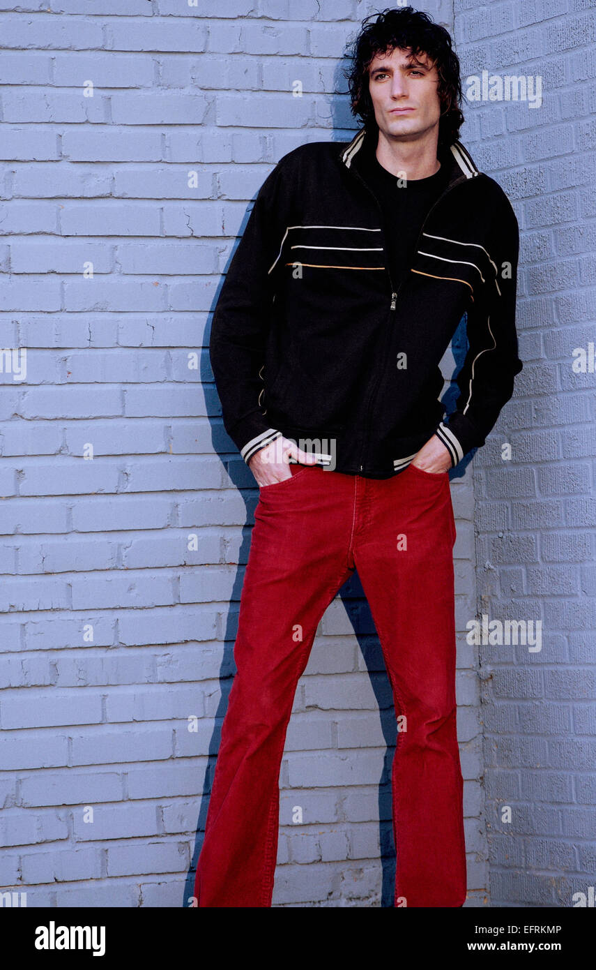 Jeune homme en pantalon rouge et noir blouson rayé, habillé négligemment et  traîner autour de l'extérieur, contre le mur de briques Photo Stock - Alamy
