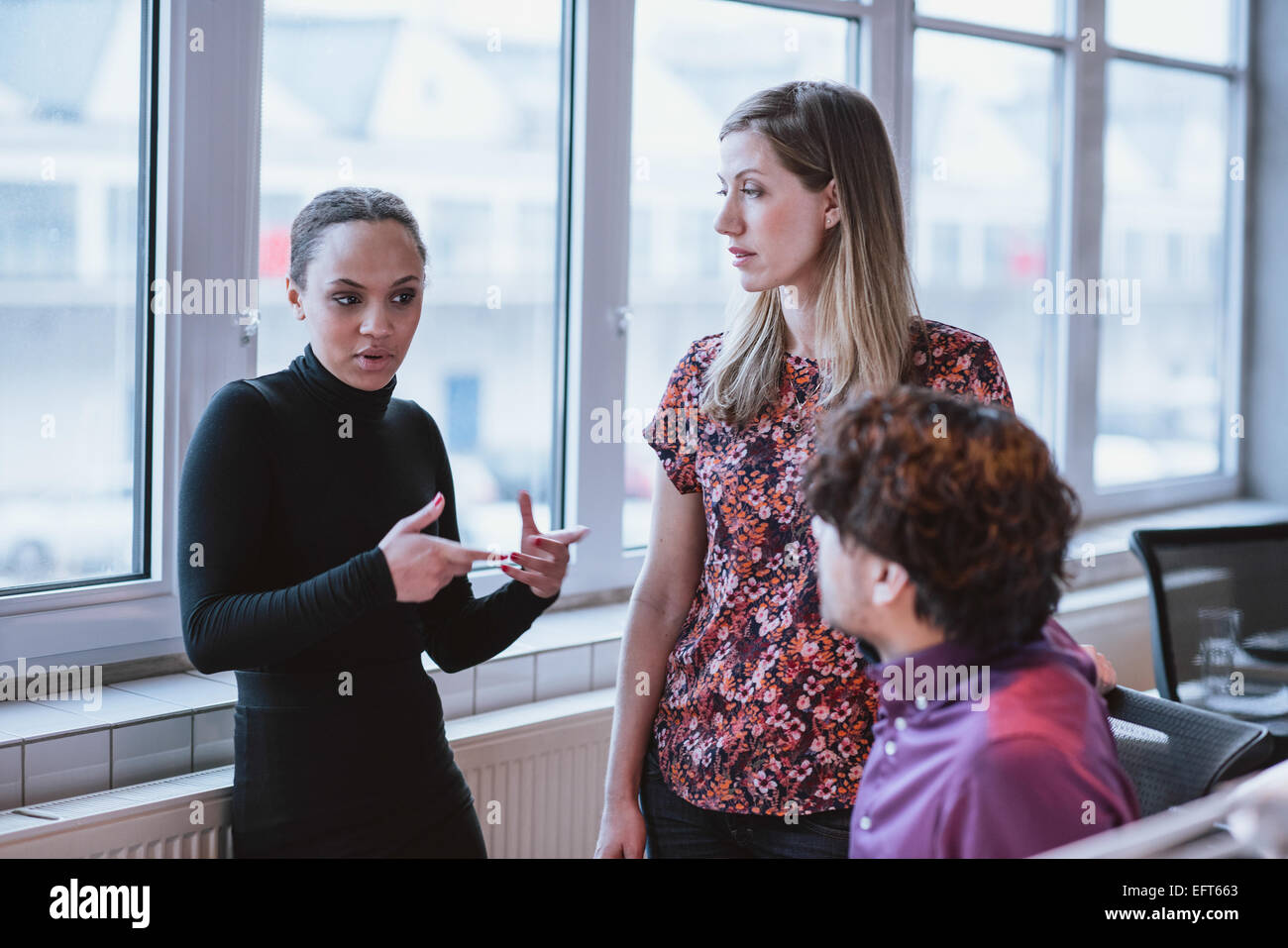 Jeune femme expliquant la stratégie de l'entreprise à ses collègues. Couple multiracial en travail social. Banque D'Images