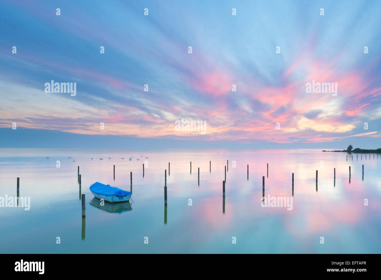 Un beau coucher du soleil calme et tranquille avec des couleurs bleu et rose, un petit bateau sur un lac et ciel spectaculaire en Hollande Banque D'Images