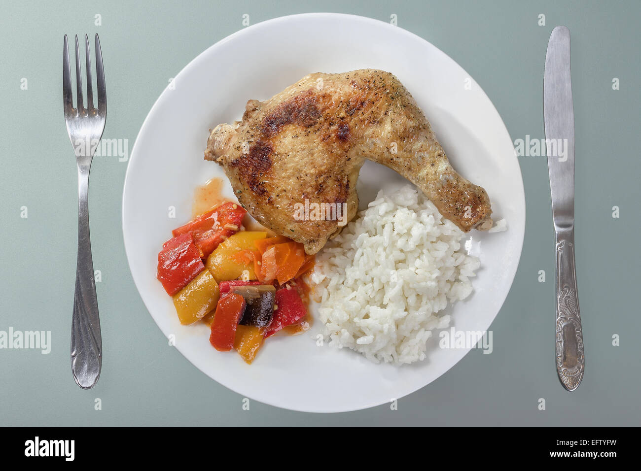 Cuisse de poulet rôti avec du riz et des légumes sur une plaque blanche. Banque D'Images