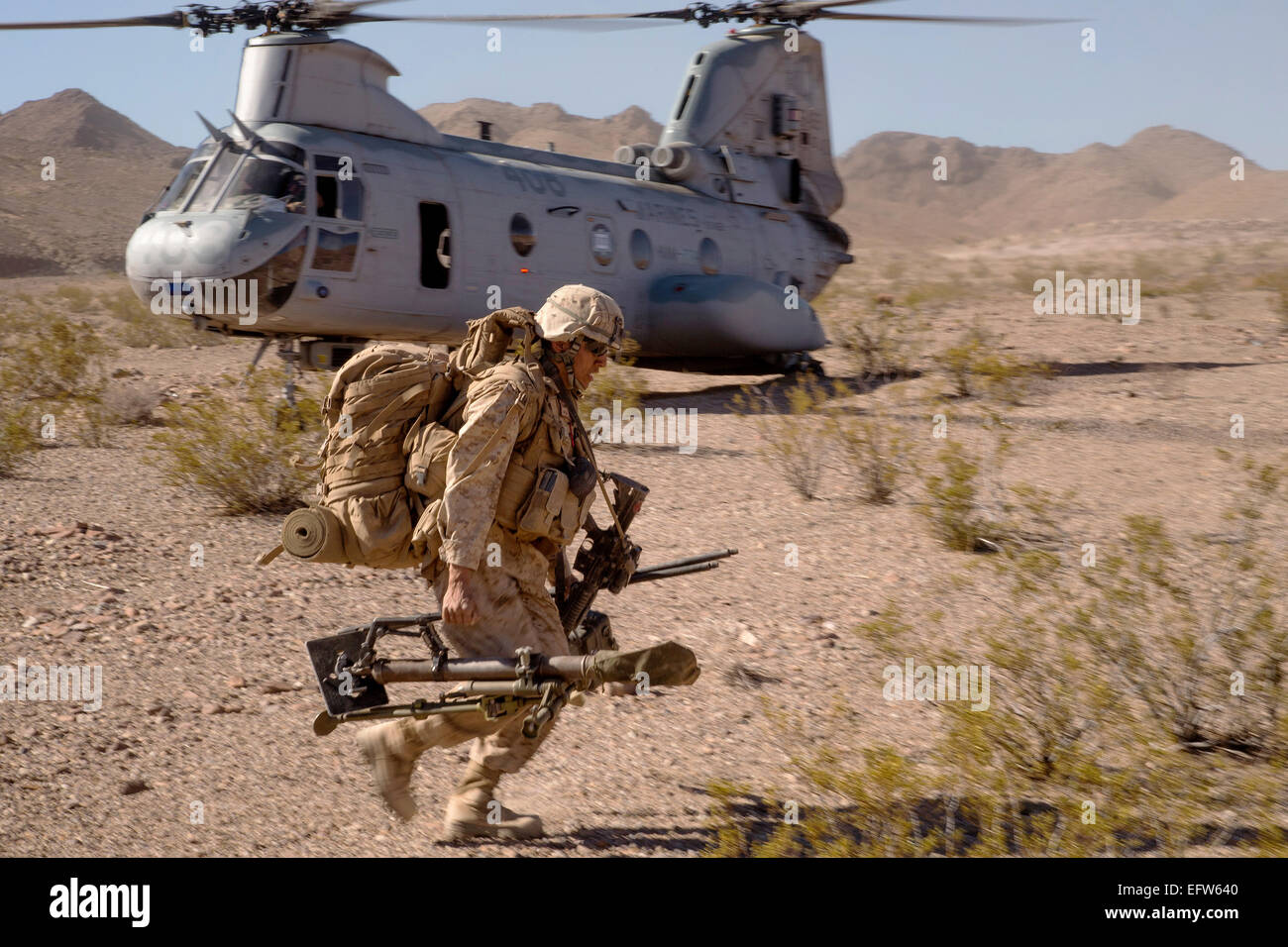 Un Marine américain porte un équipement déchargé de l'hélicoptère CH-46 Sea Knight pendant un exercice de formation intégrée, 20 juin 2013 à la Base du Corps des Marines, en Californie Twentynine Palms. Banque D'Images