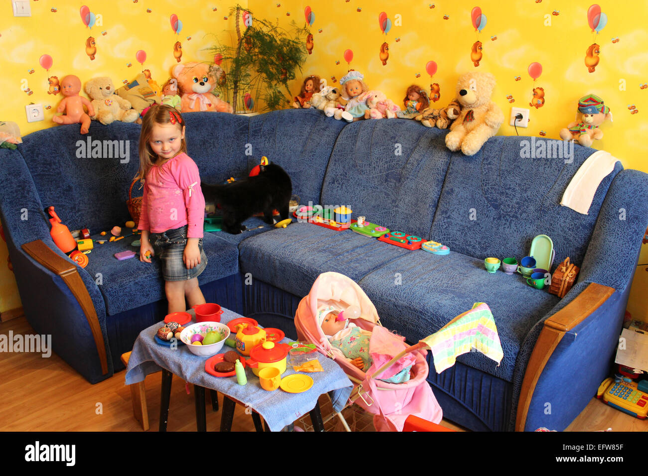 Petite fille jouant avec les jouets et les chat dans sa chambre Banque D'Images