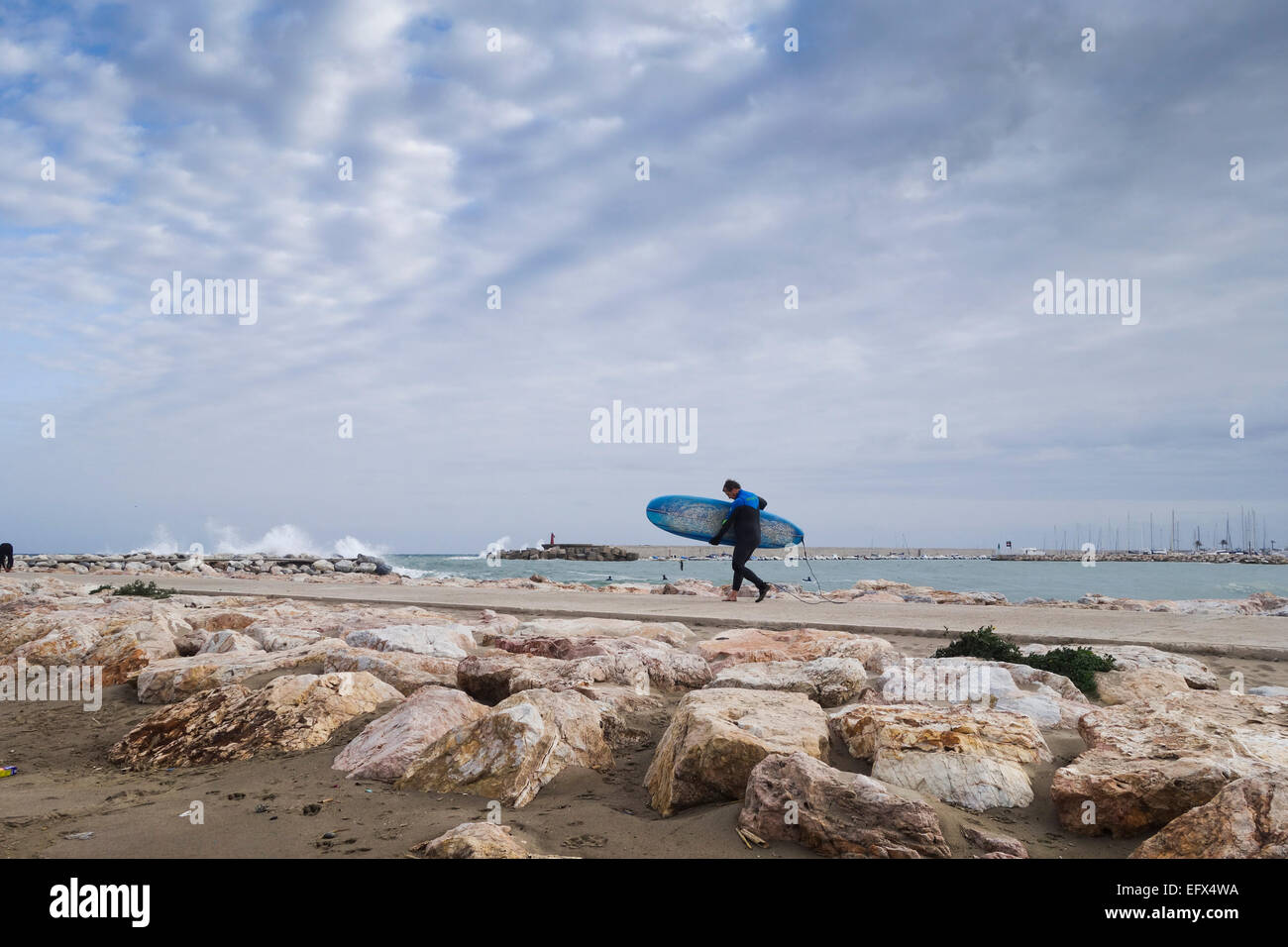 Promenades surfeur d'une jetée de pierre de surfer les vagues en cas de mauvais temps et de hautes vagues, mer agitée, Fuengirola, Malaga, Espagne. Banque D'Images