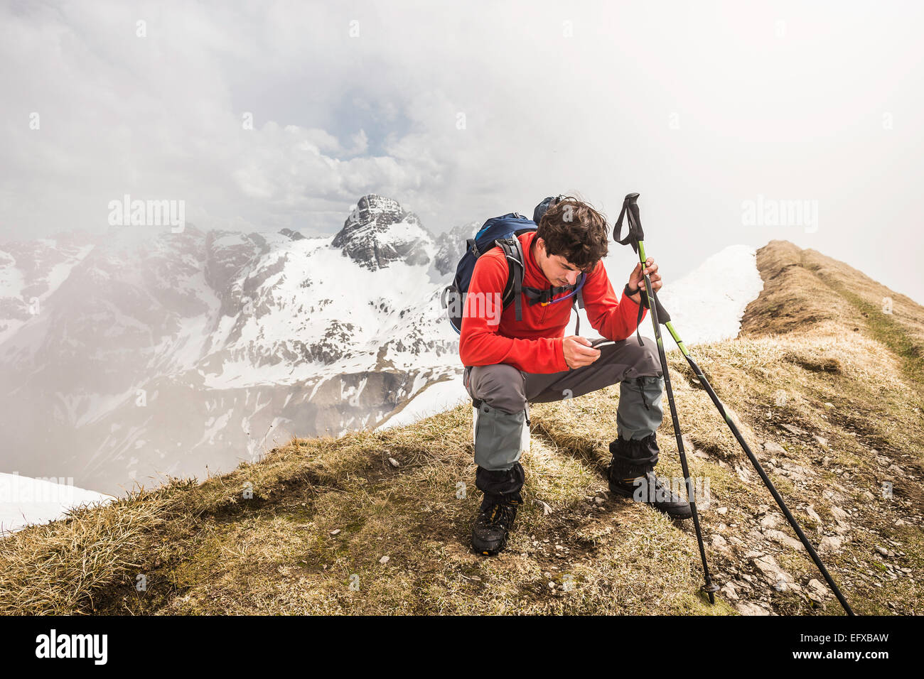 Jeune homme trekker mountain texting on smartphone in Alpes bavaroises, Oberstdorf, Bavière, Allemagne Banque D'Images