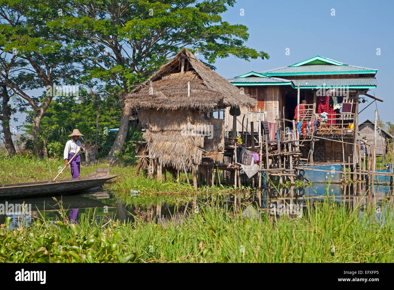 Dans l'homme ethnie Intha proa à lakeside village avec des maisons sur pilotis en bambou dans le lac Inle, Nyaungshwe, Shan State, Myanmar / Birmanie Banque D'Images