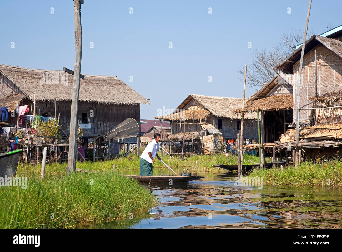 Dans l'homme ethnie Intha proa au village traditionnel avec des maisons sur pilotis en bambou dans le lac Inle, Nyaungshwe, Shan State, Myanmar / Birmanie Banque D'Images