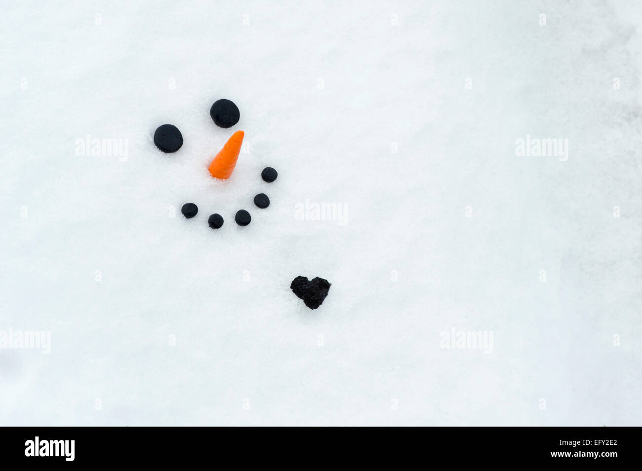 Joyeux bonhomme de face avec un grand coeur de charbon dans la neige Banque D'Images