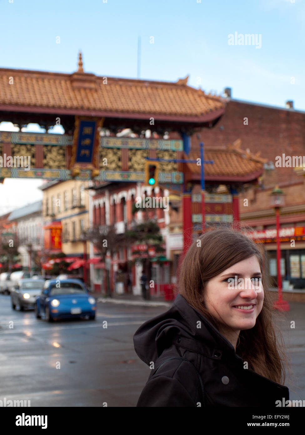 Une jolie fille brune devant la porte de l'Intérêt harmonieux dans Chinatown, Victoria, Colombie-Britannique, Canada. Banque D'Images