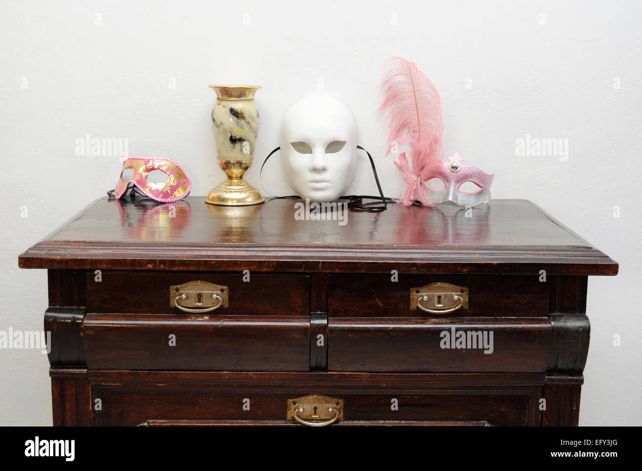 Une collection de masques et d'un vieux gobelet sur la commode vintage Banque D'Images Une collection de masques et d'un vieux gobelet sur la commode vintage Banque D'Images