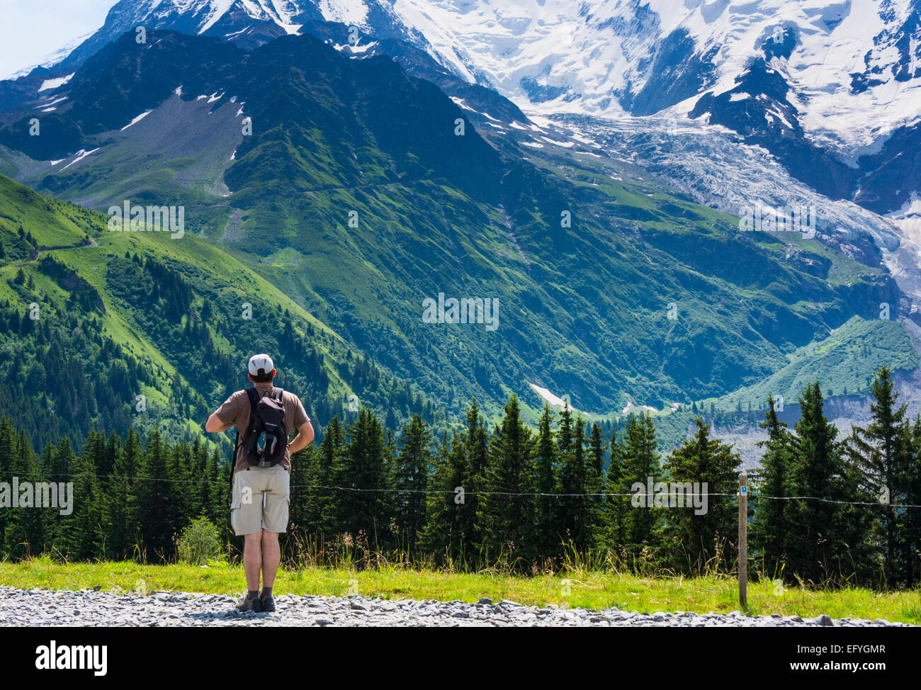 Randonneur en marche regardant vers les pentes inférieures du Mont Blanc et le Glacier de Bionnassay, Chamonix, Alpes françaises, France, Europe en été Banque D'Images