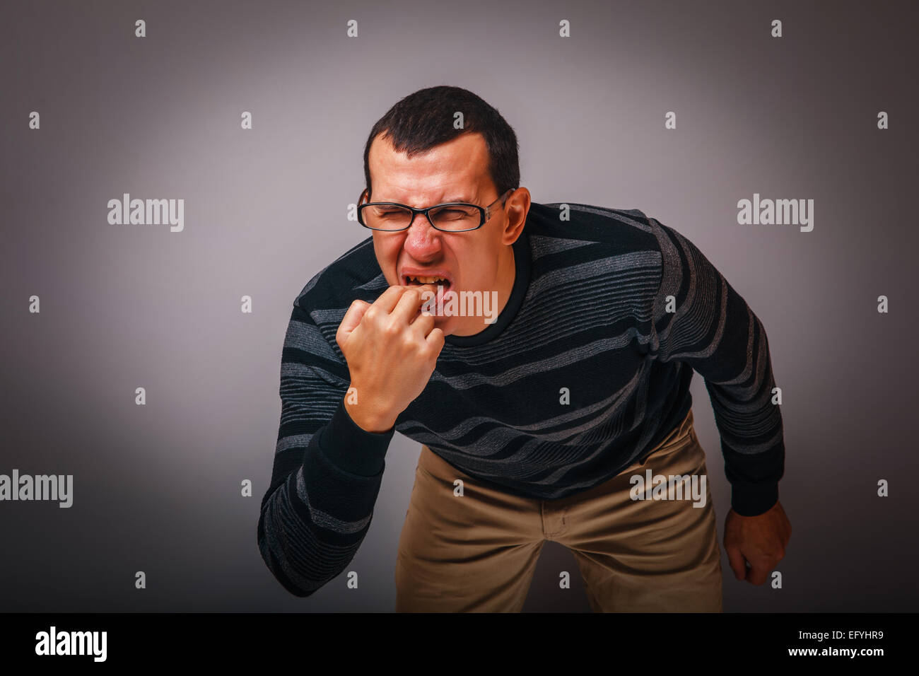Homme d'apparence brunet mettre ses doigts dans sa bouche Banque D'Images