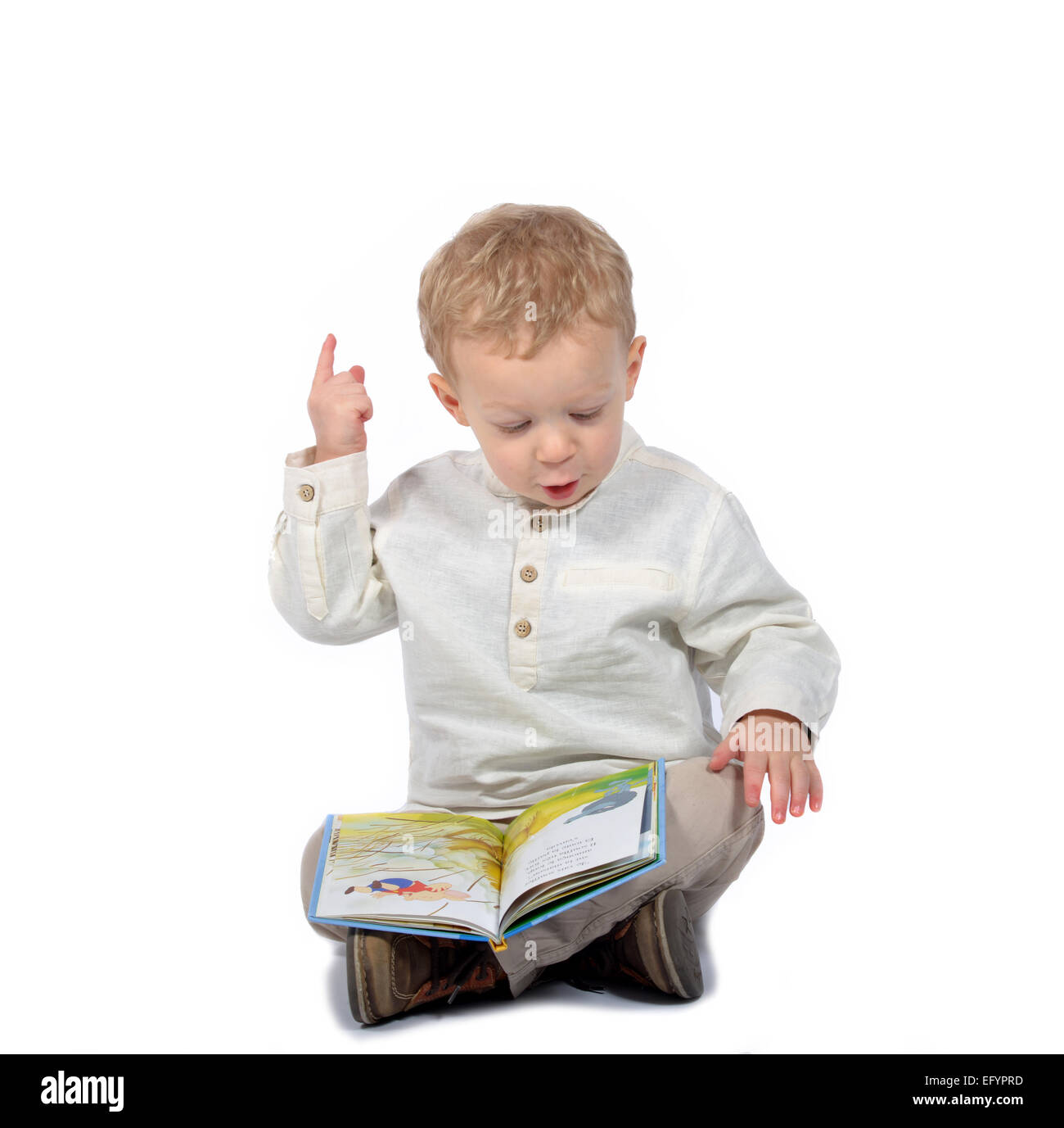 Bébé vêtu d'une chemise blanche assis en tailleur la lecture d'un livre Banque D'Images