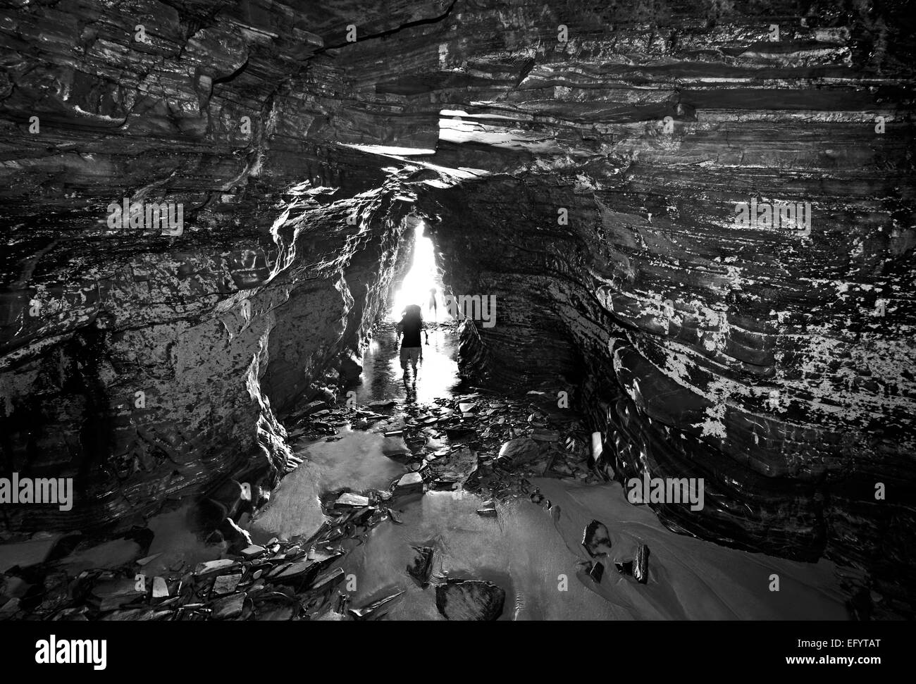 L'Espagne, la Galice : personnes marchant à l'intérieur d'une grotte à Cathedral's Beach en version noir et blanc Banque D'Images