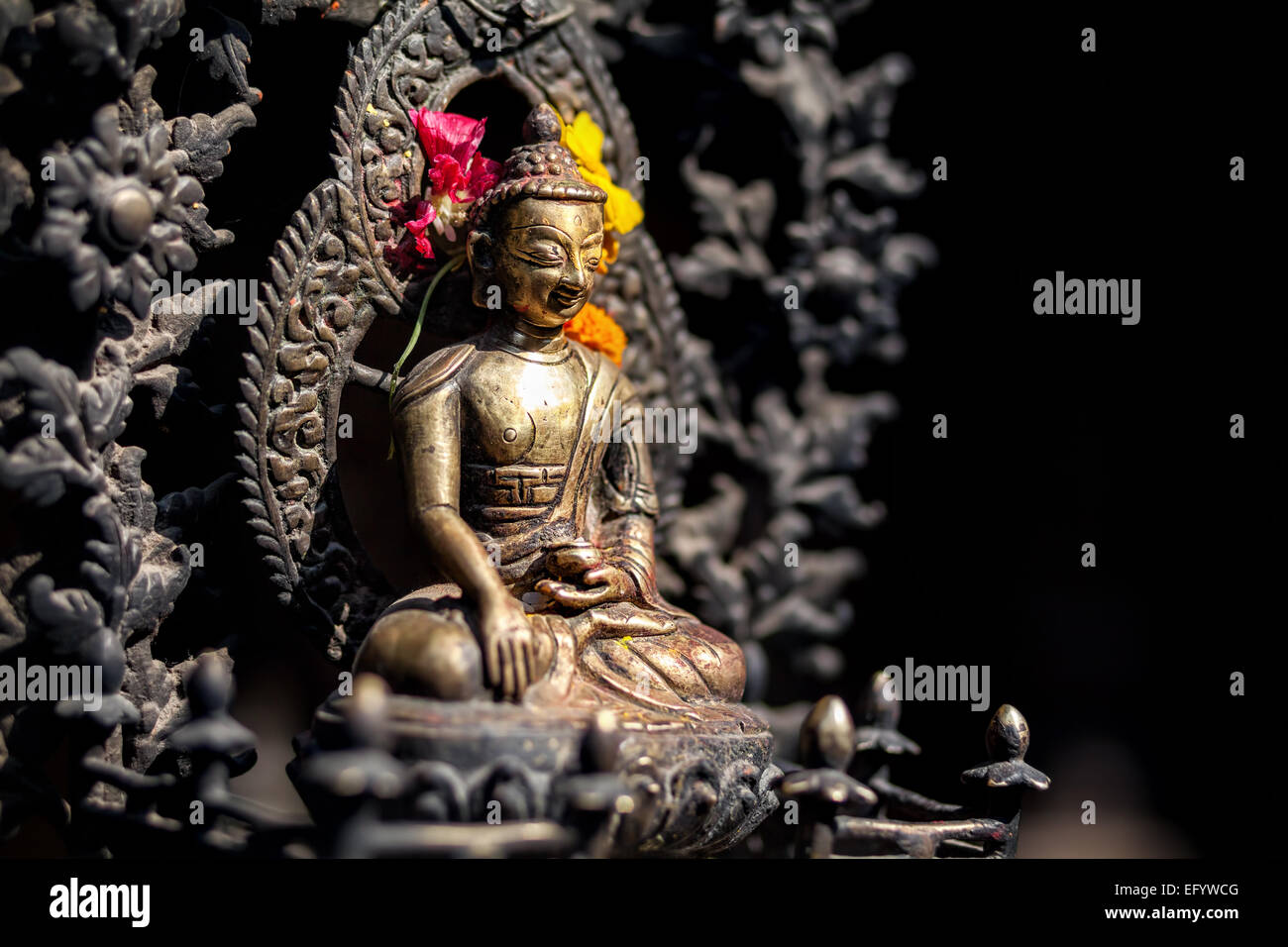 Statue de Bouddha avec des fleurs jaunes et rouges à Patan, Népal Banque D'Images