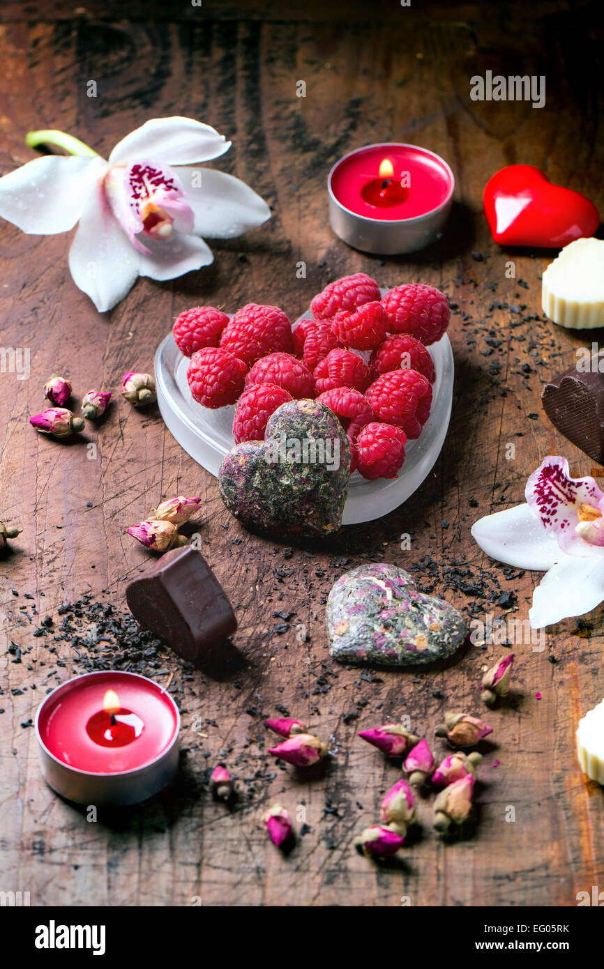 Bonbons de chocolat en forme de coeur avec des roses thé sec, framboises fraîches et d'orchidées pour la Saint-Valentin. Banque D'Images