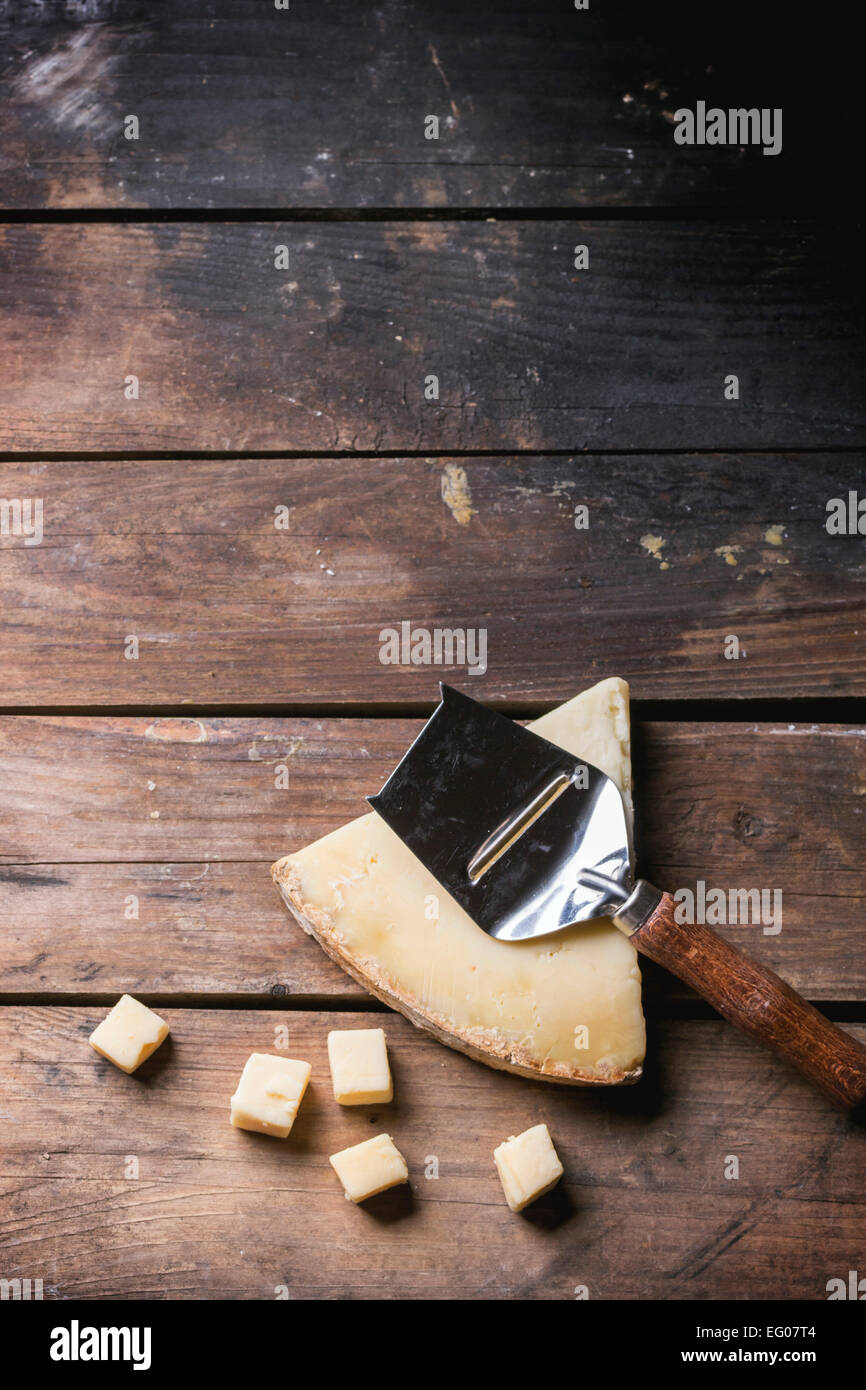 Gros morceau et de petits cubes de fromage avec du fromage belge à couteau sur fond de bois. Vue d'en haut. Banque D'Images