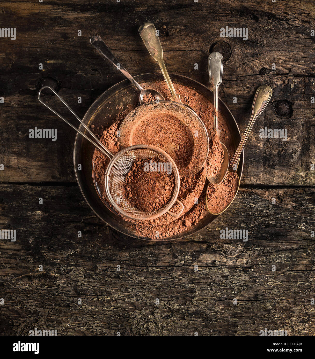 Le chocolat en poudre dans metall plaque avec des cuillères en bois foncé sur arrière-plan, Vue de dessus Banque D'Images