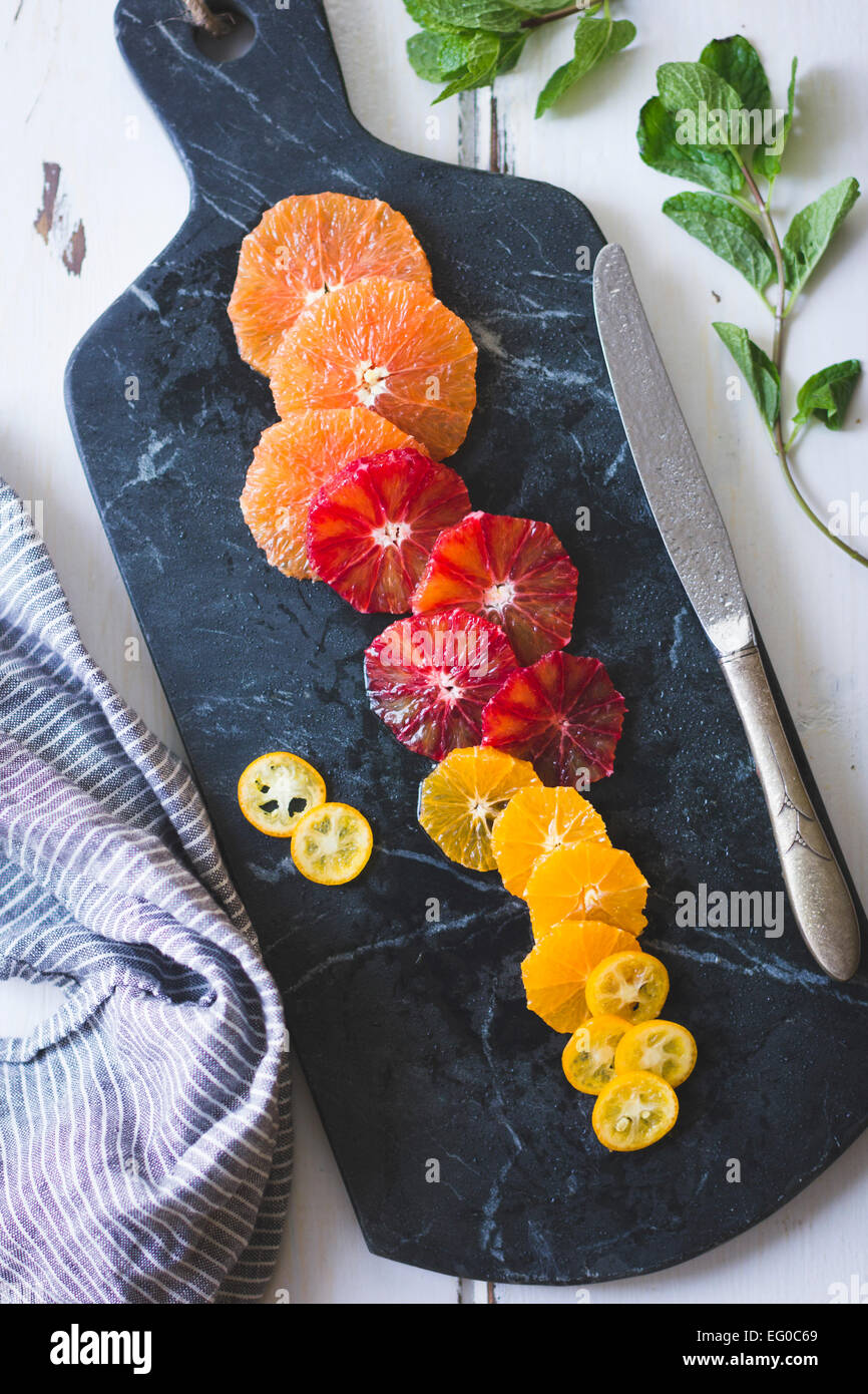 Agrumes sur une planche à découper en marbre. Banque D'Images