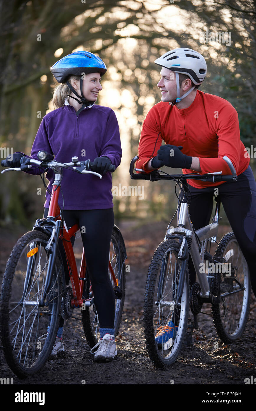 Couple Riding Mountain Bikes à travers des bois Banque D'Images