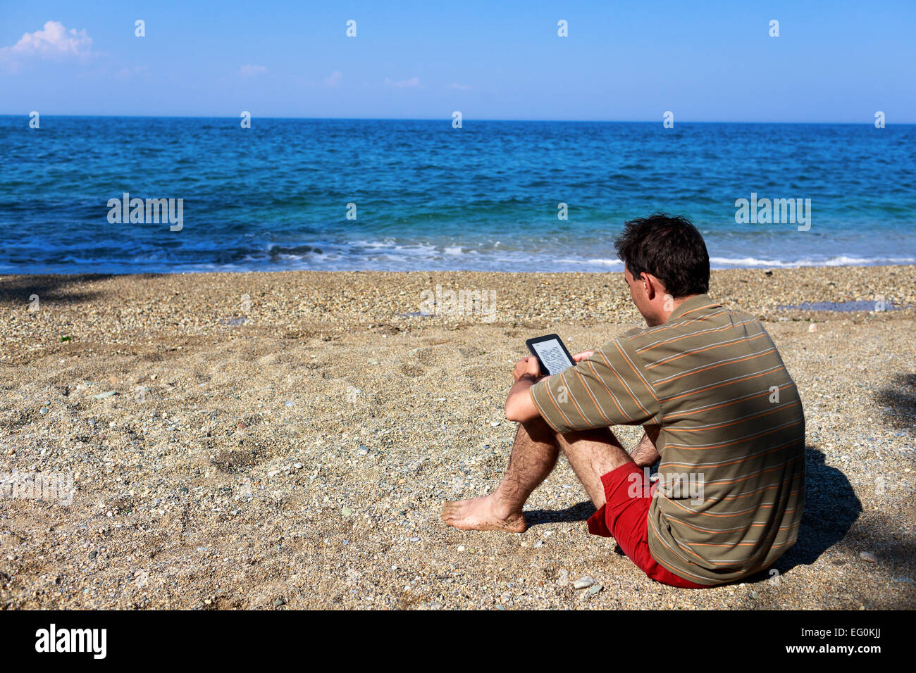 Homme assis sur la plage de lecture, Thessalonique, Grèce Banque D'Images