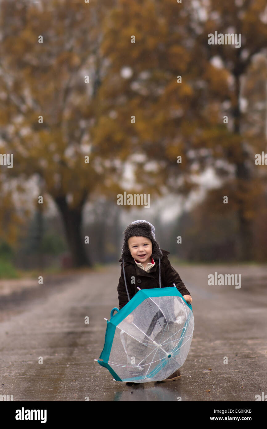 Smiling boy with umbrella on country road Banque D'Images