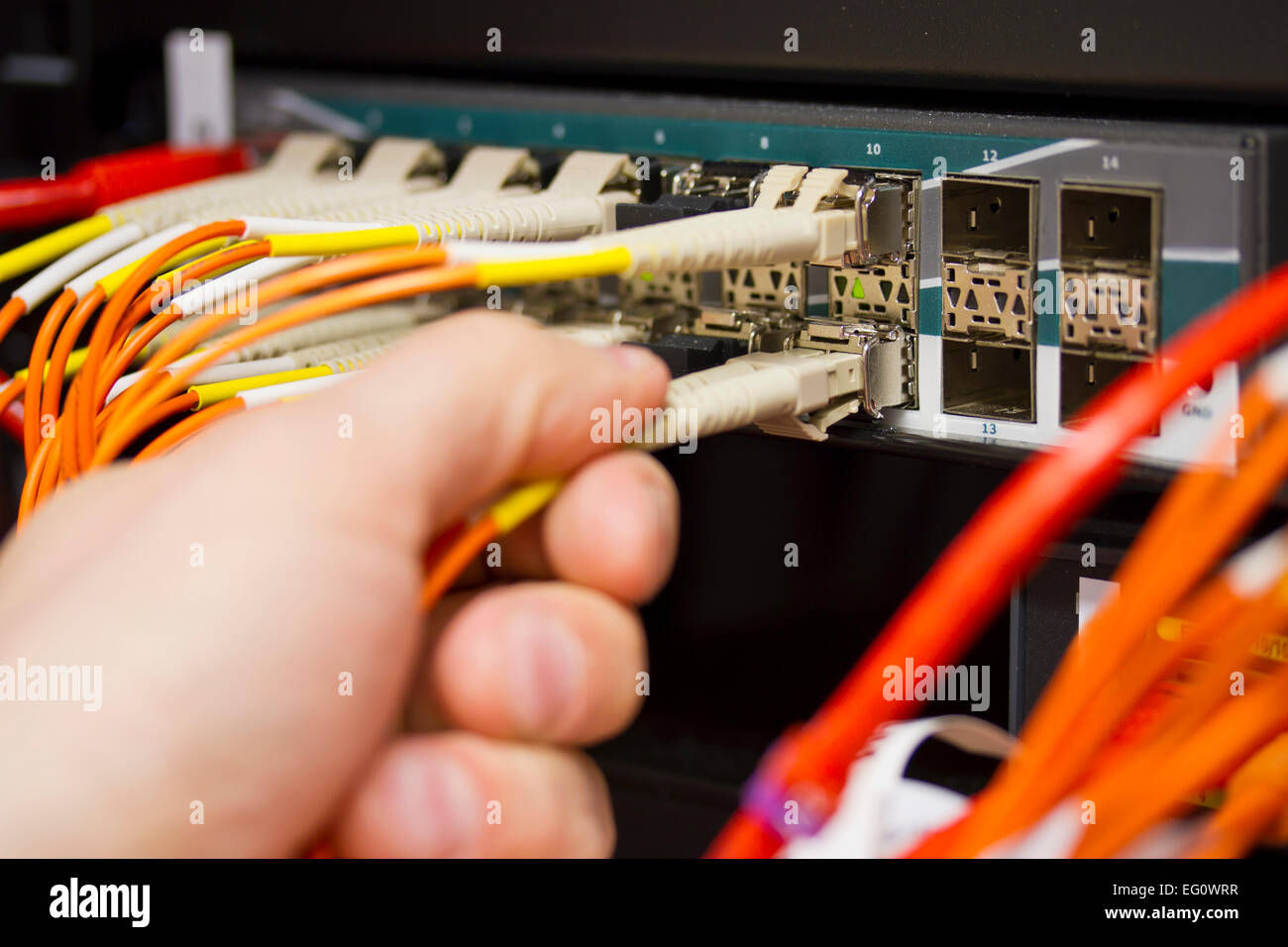 Insérez un câble à fibres optiques dans un commutateur en datacenter. Banque D'Images