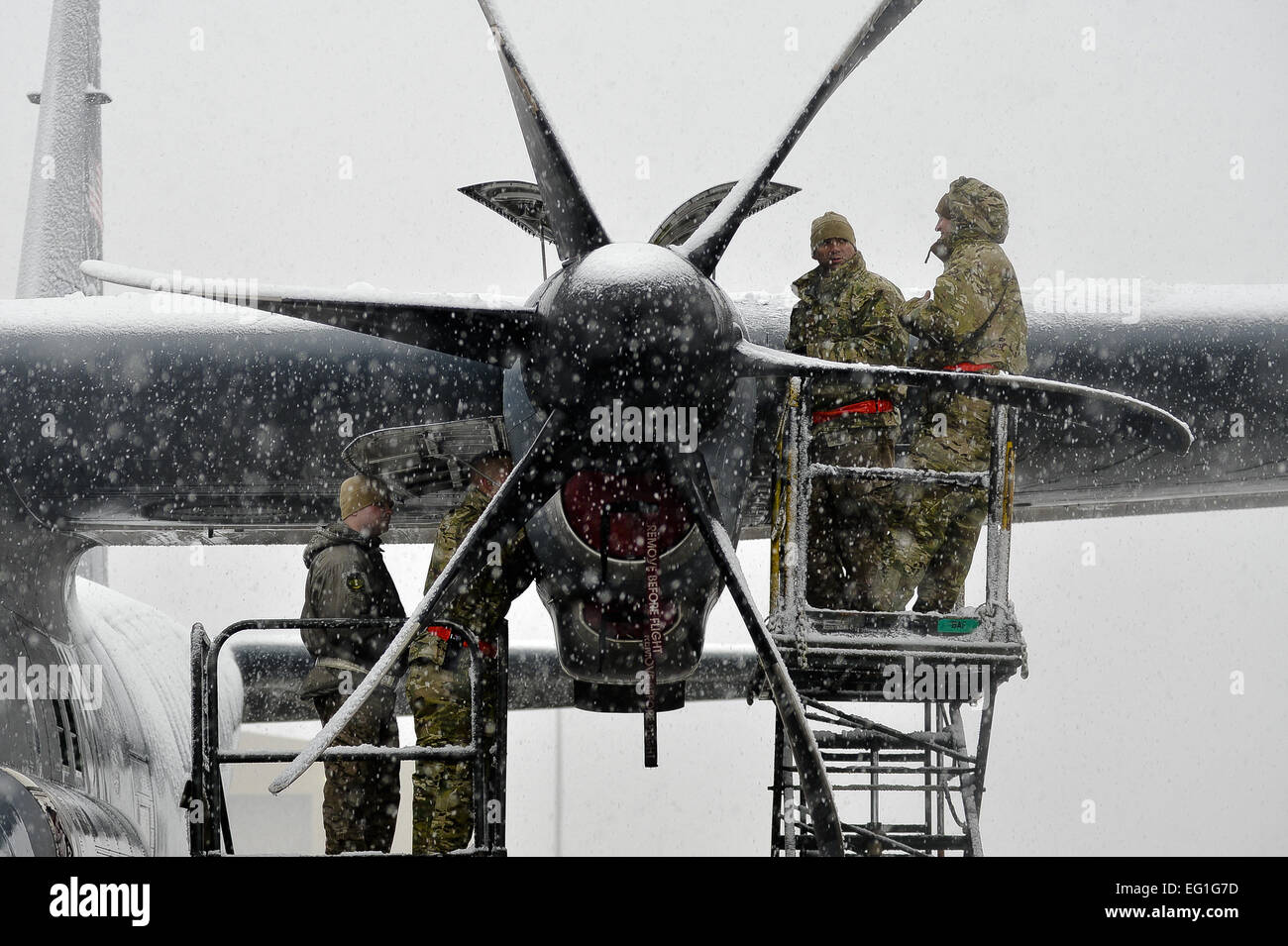 Aviateurs avec le 455 e Escadron de maintenance des aéronefs de la Force expéditionnaire du travail sur le moteur d'un C-130J Super Hercules lors de chutes de neige le 6 février 2014, l'air à Bagram, en Afghanistan. Neige a commencé vers 14 h 30, et on prévoit une accumulation maximale de 4 pouces. Kayla Newman Senior Airman Banque D'Images