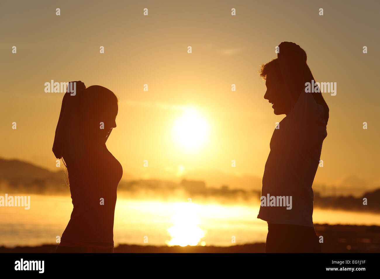 Silhouette d'un couple stretching remise en forme au lever du soleil avec le soleil en arrière-plan Banque D'Images