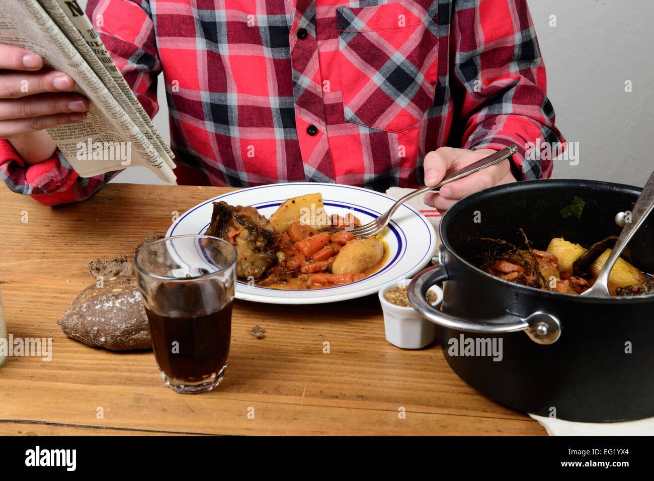 Un homme mange carotte boeuf et lire un journal Banque D'Images