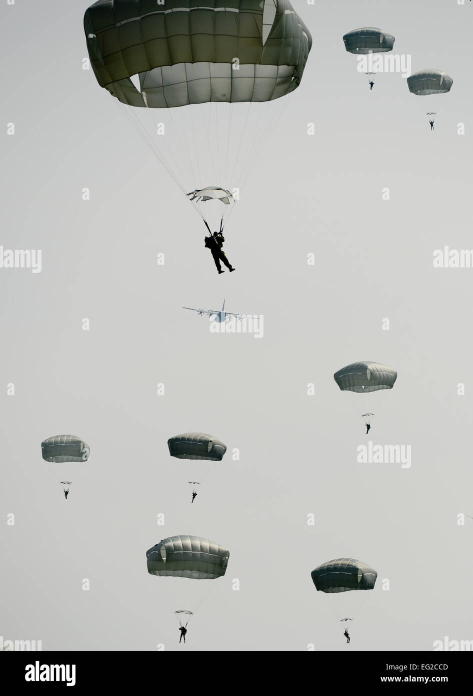 Les parachutistes de descendre lentement vers le sol comme un C-130 vole au loin dans la distance pendant la semaine de Saut International le 5 mai 2014, à l'Alzey zone d'atterrissage, de l'Allemagne. Plus de 300 cavaliers provenant de neuf pays différents a effectué 404 sauts en ligne à l'électricité statique et à faible altitude 132 sauts d'ouverture en trois jours. Un membre de la 1re classe Michael Stuart Banque D'Images