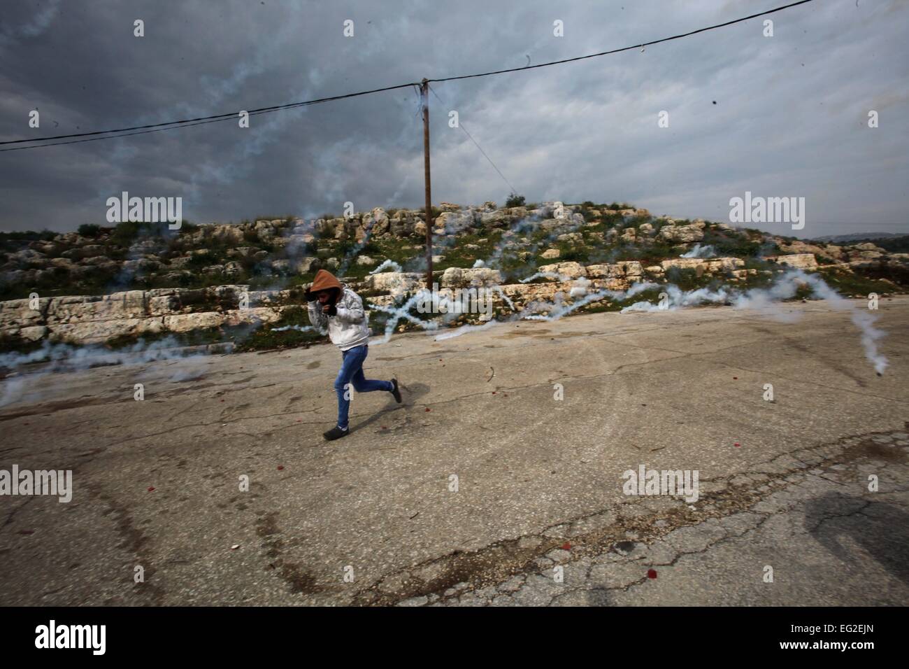 Qalqilya en Cisjordanie, territoire palestinien. Feb 14, 2015. Un manifestant palestinien s'enfuit de gaz lacrymogènes tirés par la police des frontières israéliennes au cours d'affrontements à la suite d'une protestation contre la fermeture de la route du village, dans le village d'Azzun près de Qalqilya, 14 février 2015 © Nedal Eshtayah/APA/Images/fil ZUMA Alamy Live News Banque D'Images