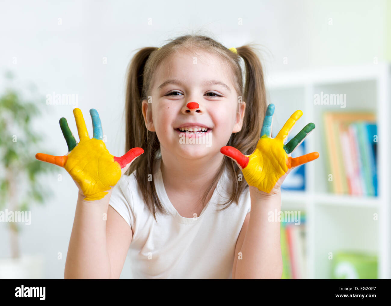 Cute kid enfant montrant ses mains peints dans des couleurs vives Banque D'Images