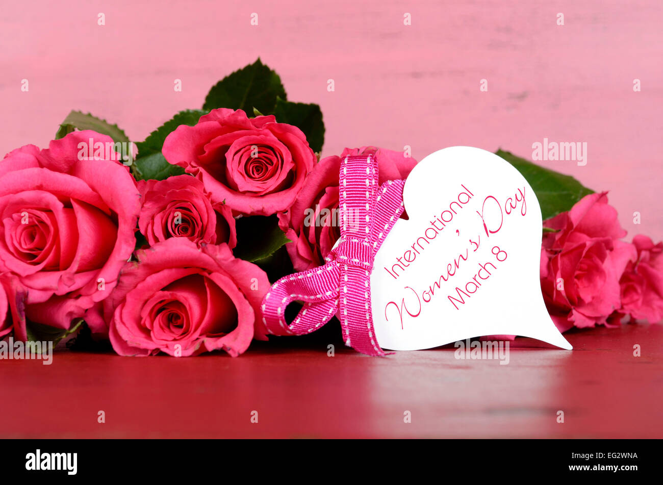 La Journée internationale des femmes, le 8 mars, avec des roses rose gift tag message sur fond de bois rose vintage. Banque D'Images